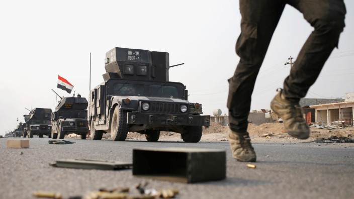 An Iraqi special forces soldier runs as other drive in armoured vehicles on a road near Mosul
