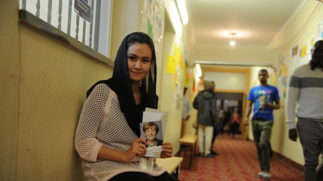 Asyl: Eine junge Frau aus der Flüchtlingsunterkunft hält eine Merkel-Autogrammkarte in die Kamera.