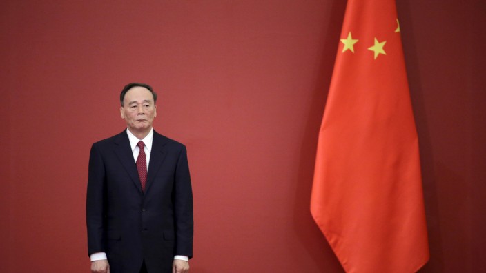 China's Politburo Standing Committee member Wang Qishan stands next to a Chinese flag in Beijing