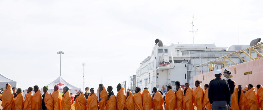 Migrants stands in line after disembarking from the Norwegian vessel Siem Pilot at Pozzallo's harbour