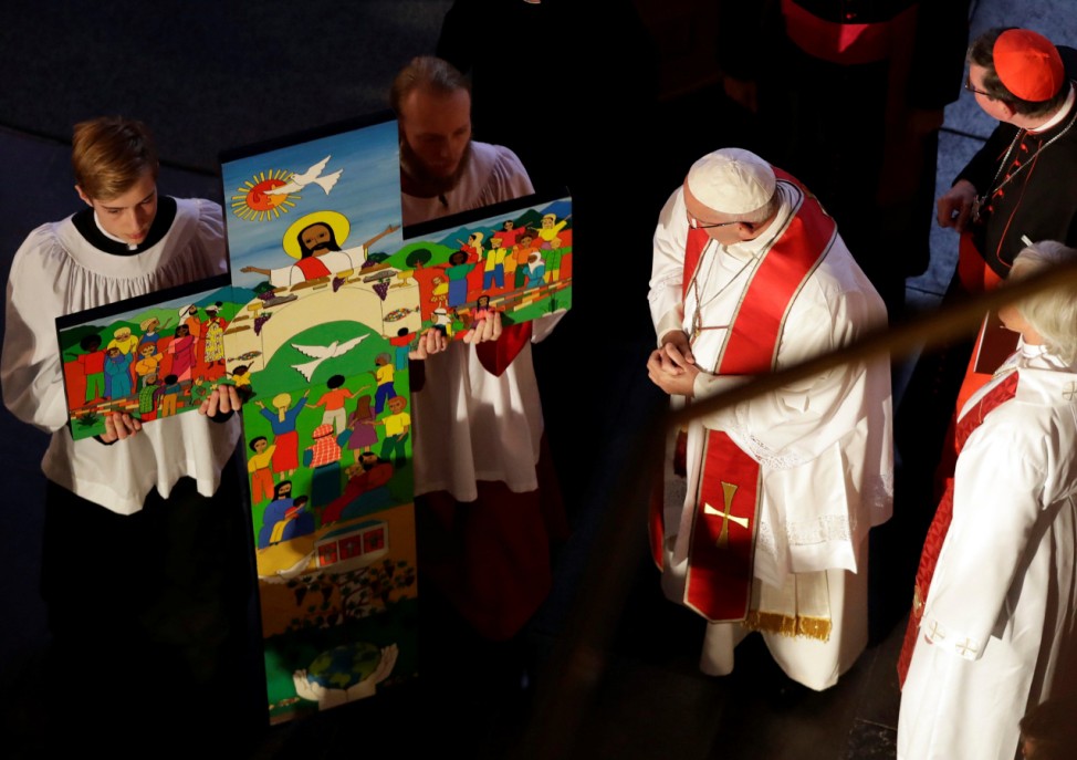 Pope Francis looks at a painted cross as he arrives for ecumenical mass in the cathedral in Lund