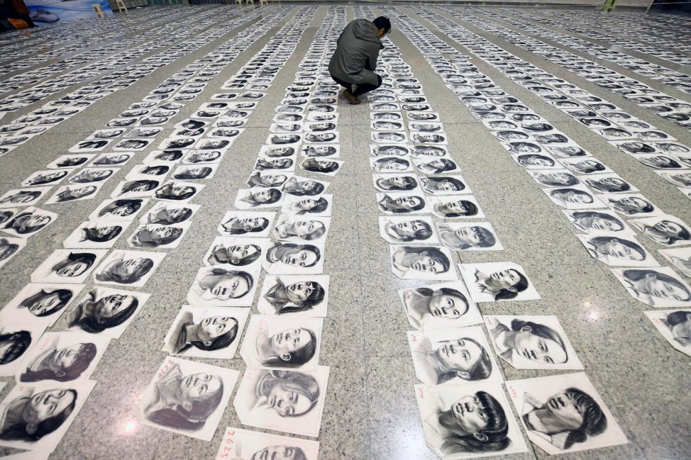 A teacher looks at sketches done by candidates taking part in mock college entrance examination in Taiyuan