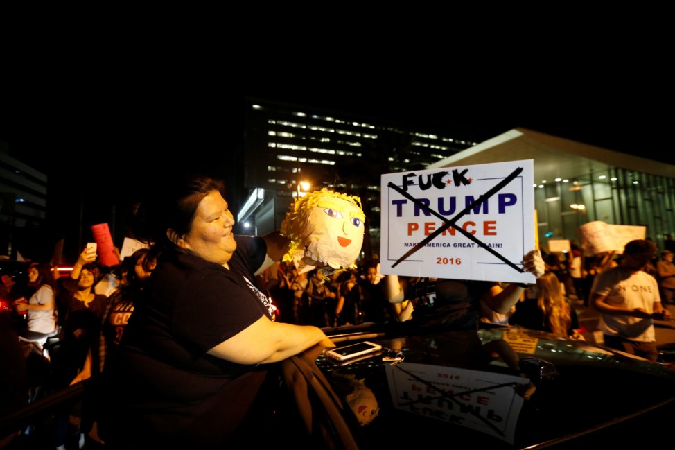 A motorist stops to put out a pinata while protesting the election of Republican Donald Trump as the president of the United States in downtown Los Angeles