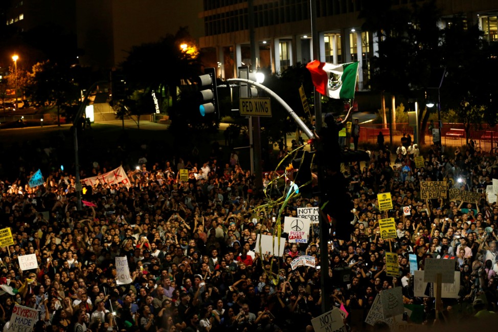 A protester waves a Mexican flag as others gather to protest to the election of Republican Donald Trump as the president of the United States outside City Hall in Los Angeles