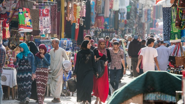 Men and covered women walking through market