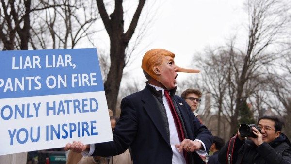 NY Anti Trump rally at Columbus Circle Activist in Trump mask with long nose wield Liar Liar Pants