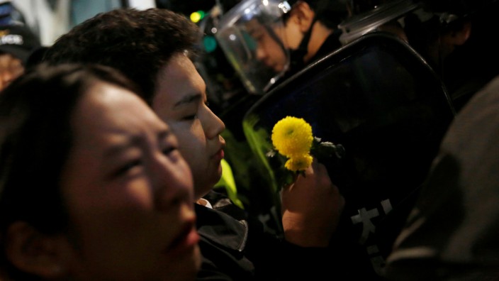 A protester holds a flower in front of riot police who block protesters on a road near the presidential Blue House during the protesters' march calling South Korean President Park to step down in Seoul