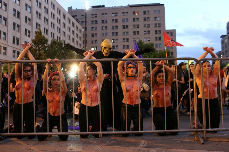 Protesters with their bodies painted depicting blood are seen as they attend a demonstration to support International Day for the Elimination of Violence Against Women in Santiago