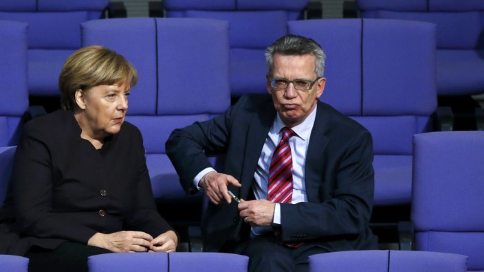 German Chancellor Merkel speaks with Interior Minister de Maiziere after a session of the German lower house of parliament, the Bundestag, in Berlin