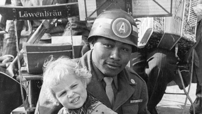 Farbiger US-Soldat mit einem Kind auf den Knien