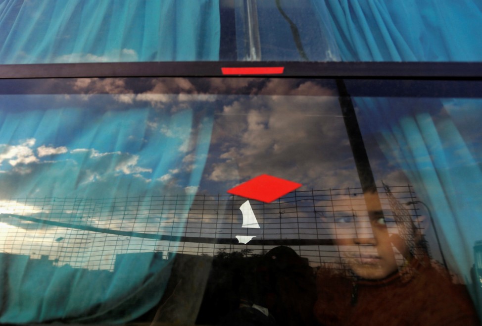 Palestinian boy looks out through a bus window as he waits with his family to cross into Egypt through the Rafah border crossing after it was opened by Egyptian authorities for humanitarian cases, in Rafah in the southern Gaza Strip