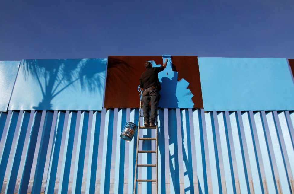 An artist paints a part of a section of the wall separating Mexico and the United States as seen from Playas Tijuana