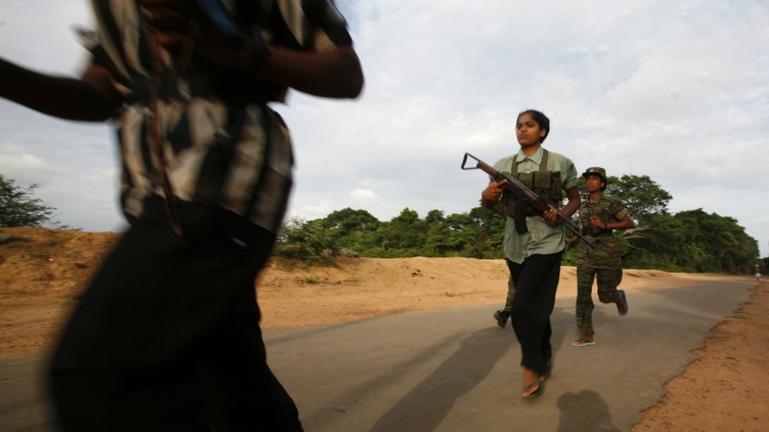 Female Tamil Tiger rebels run on a street as they head back to base after an overnight guard duty in Kilinochchi