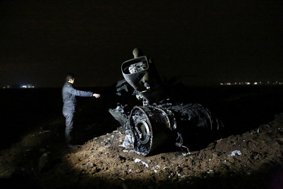 A television reporter points at the wreckage of a Turkish Air Force F-16 fighter jet after it crashed in an empty field in the southeastern city of Diyarbakir