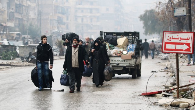 People carry their belongings as they flee deeper into the remaining rebel-held areas of Aleppo