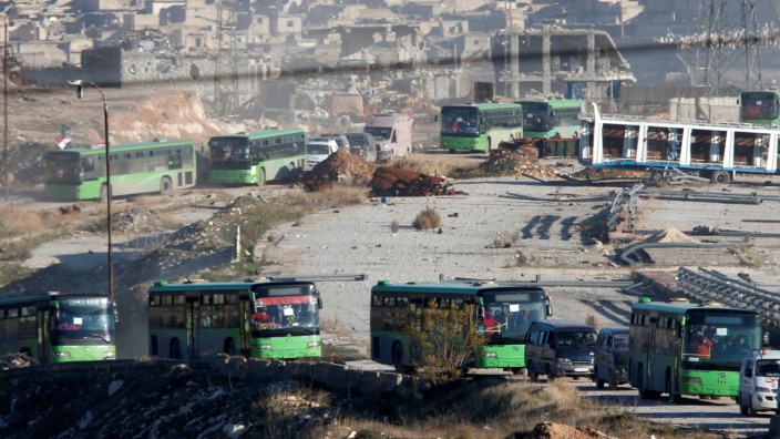 Ambulances and buses evacuating people drive out of a rebel-held part of Aleppo