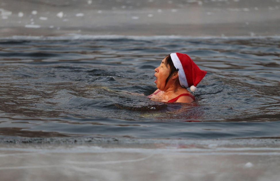 A winter swimmer wearing a Christmas hat swims in a half-frozen lake in Shenyang