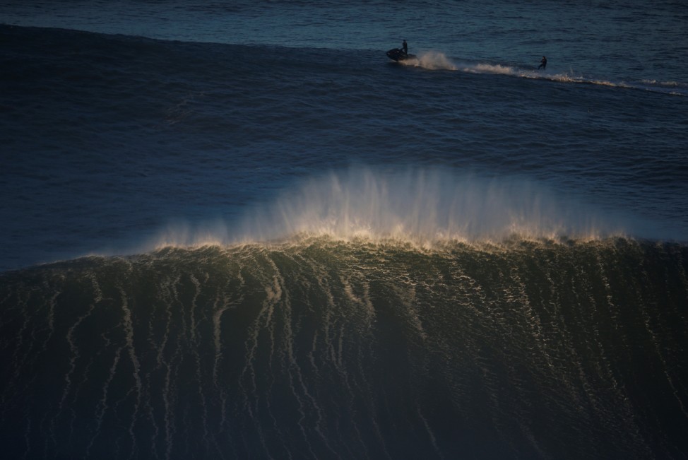 A surfer drops in on a large wave at Praia do Norte in Nazare