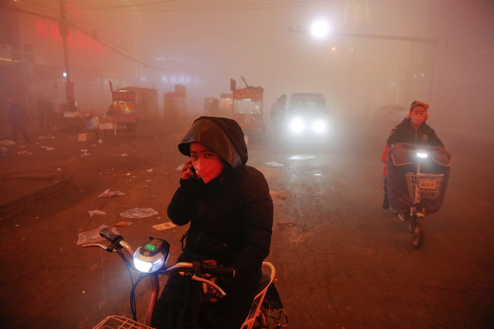 People make their way through heavy smog on an extremely polluted day with red alert issued, in Shengfang