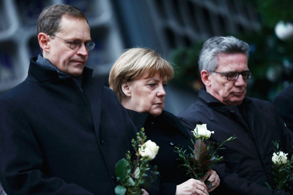 Berlin mayor Mueller, German Chancellor Merkel and German interior minister de Maiziere stand in silence at the Christmas market in Berlin