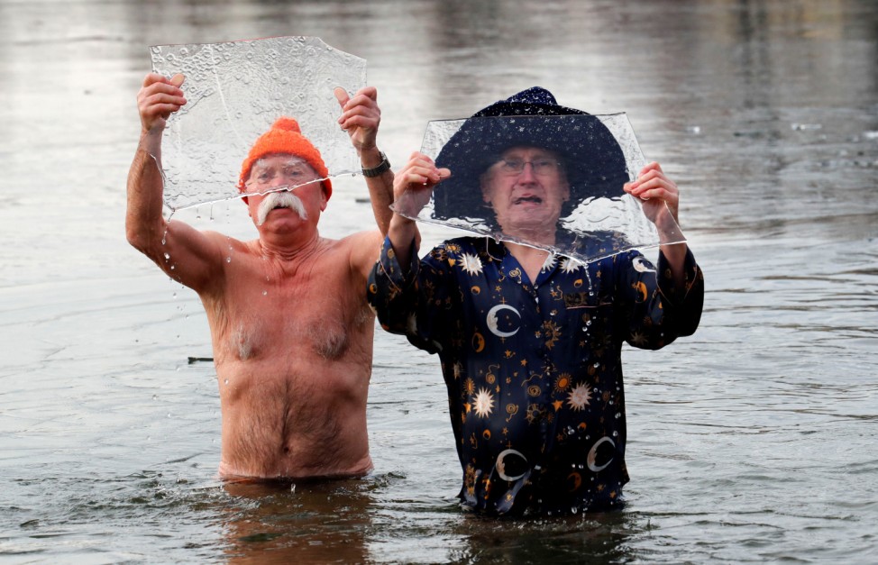 Members of the Berlin Seals ice swimmers club hold ice as they take a dip in lake Orankesee during their traditional New Year swimming event in Berlin