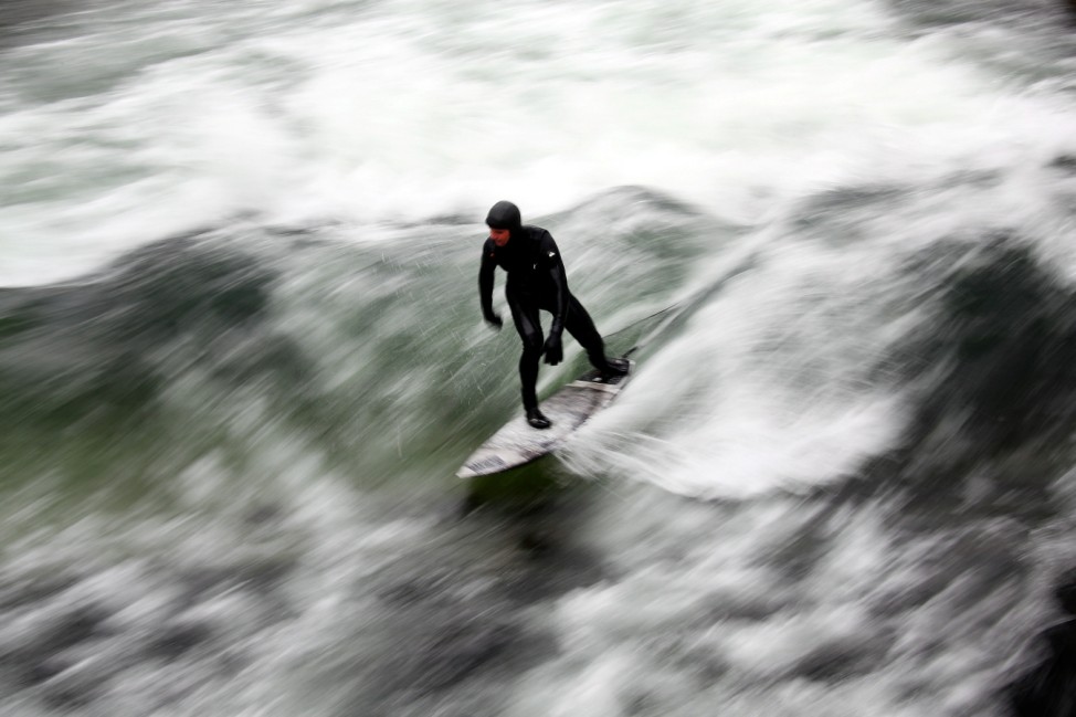 A surfer catches a wave on a freezing water of the Eisbach in Munich