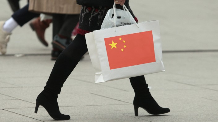 Symbolbild privater Konsum und Kaufkraft Frau mit Stiefeln trägt eine Tragetasche mit Flagge China