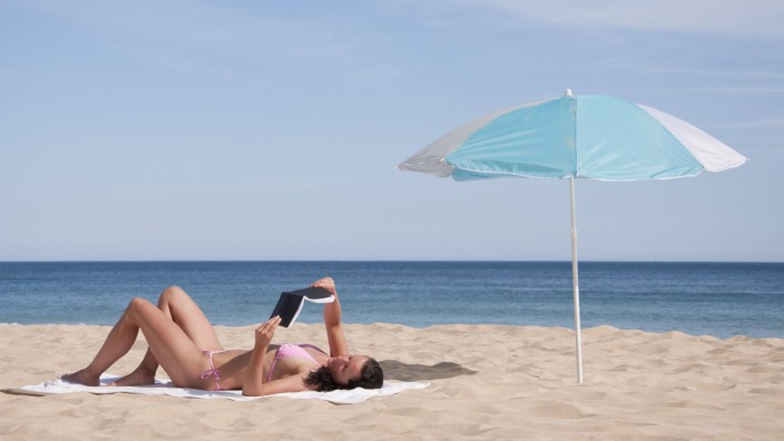 Portugal Lagos Mid adult woman reading book on beach model released PUBLICATIONxINxGERxSUIxAUTxHUN