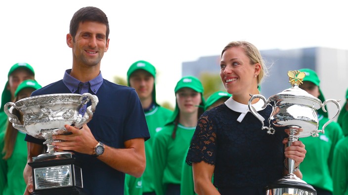 Current Australian Open tennis champions Serbia's Novak Djokovic and Germany's Angelique Kerber walk together as they hold the tournament trophies ahead of the official draw ceremony in Melbourne, Australia