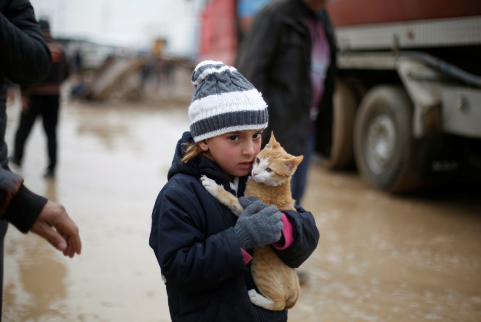 Malac holds her cat as she walks back with her family to their home from Khazer camp