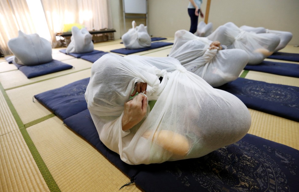 Participants perform Otonamaki, which translates as 'adult wrapping', a new form of therapy where people are wrapped in large swaddling cloth to alleviate posture problems and stiffness, at a session in Asaka