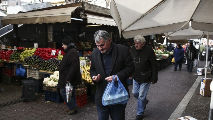 Griechenland: Ein Mann zählt Geld auf einem Gemüsemarkt in Athen - Kreditgeber und Politiker streiten über weitere Hilfen.