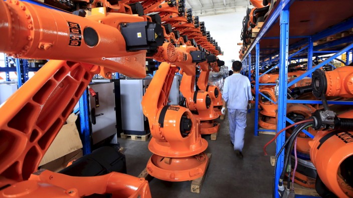File picture of a worker walking past second-hand robots in a factory in Shanghai