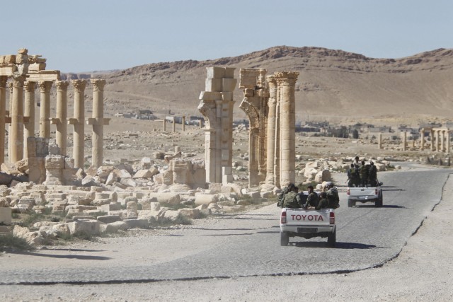 FILE PHOTO: Syrian army soldiers drive past the Arch of Triumph in the historic city of Palmyra, in Homs Governorate
