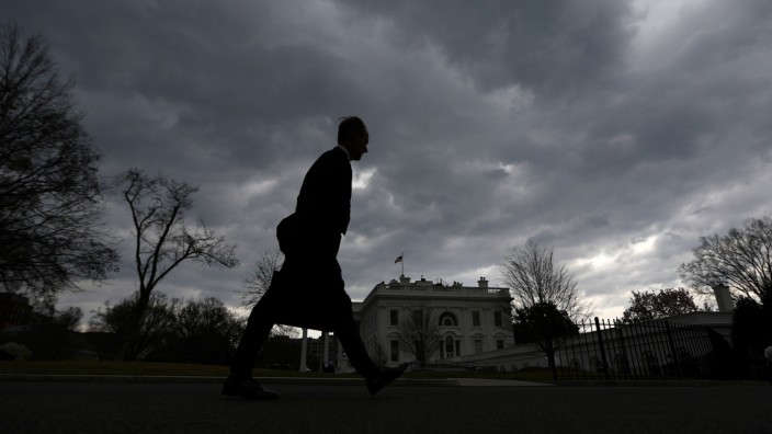 A man walks on the North Lawn of the White House as a thunderstorm approaches the Washington D.C. area