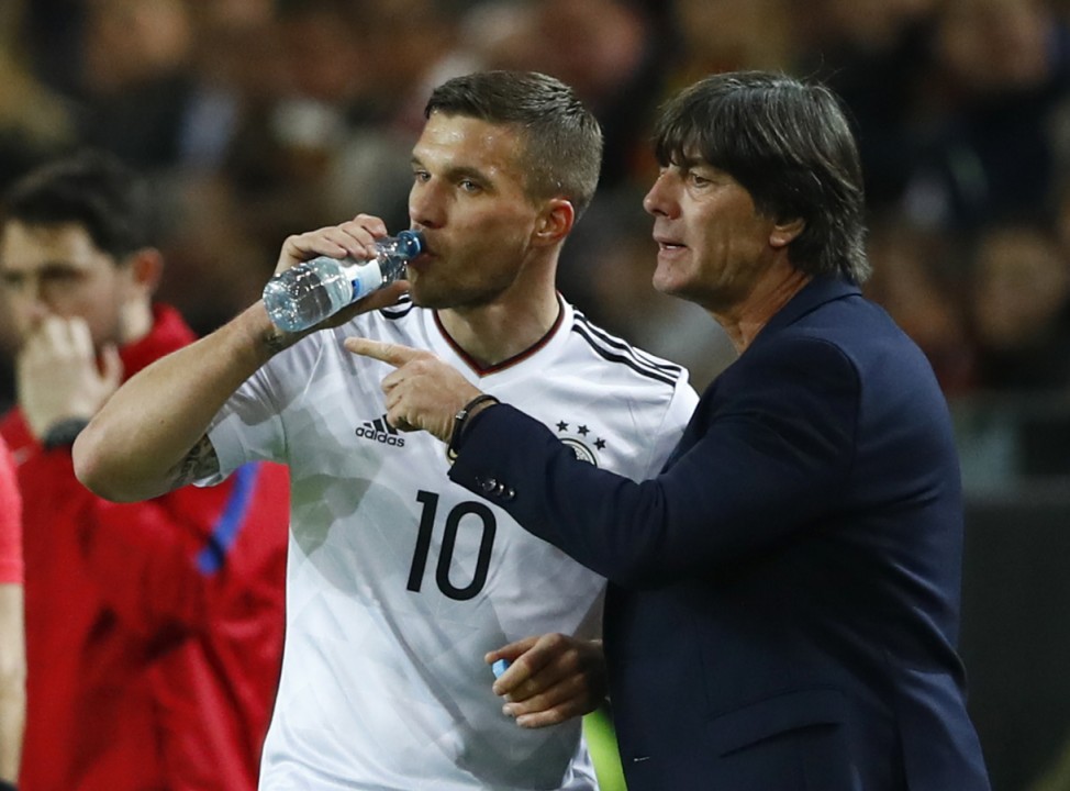 Germany's Lukas Podolski speaks with coach Joachim Low