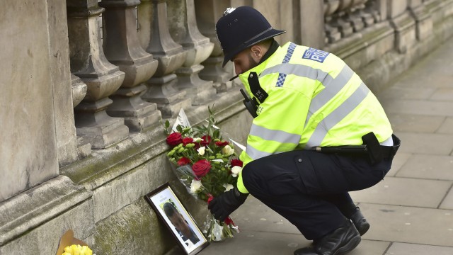Anschlag in London: Kollegen in Trauer: Ein Polizist legt in der Nähe des Parlamentssitzes Blumen nieder und ein Foto von Keith Palmer, dem unbewaffneten Polizisten, der den Londoner Attentäter stoppen wollte und dabei von ihm erstochen wurde.