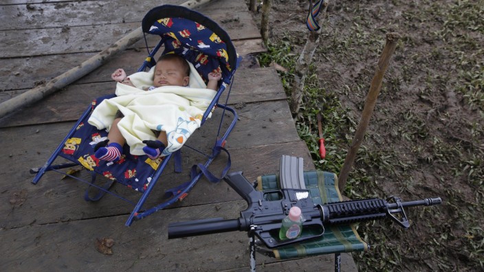 Kolumbien: Mama gibt bald die Waffe ab: Das Baby einer Farc-Kämpferin schläft in einem Rebellencamp in La Carmelita, im Südwesten Kolumbiens. Seit die Aufständischen nicht mehr gegen die Regierung kämpfen, erlebt die Guerilla einen regelrechten Babyboom.