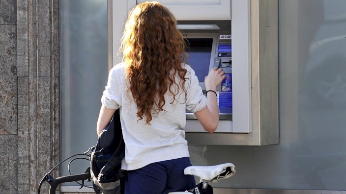 Frau mit Rennrad am Geldautomat