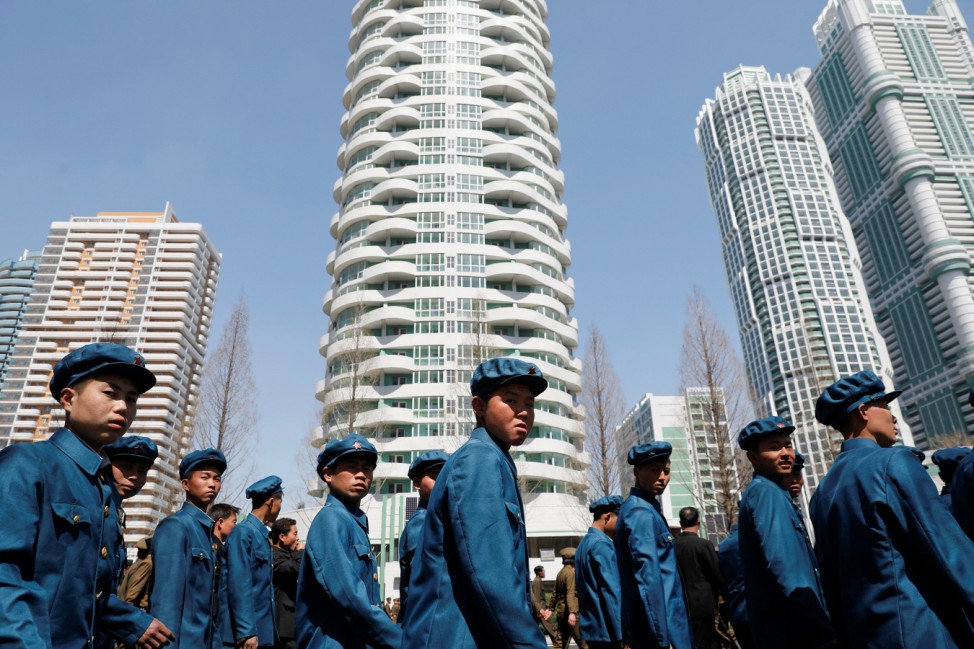 Men in uniforms walk between buildings after the opening ceremony of a newly constructed residential complex in Ryomyong street in Pyongyang