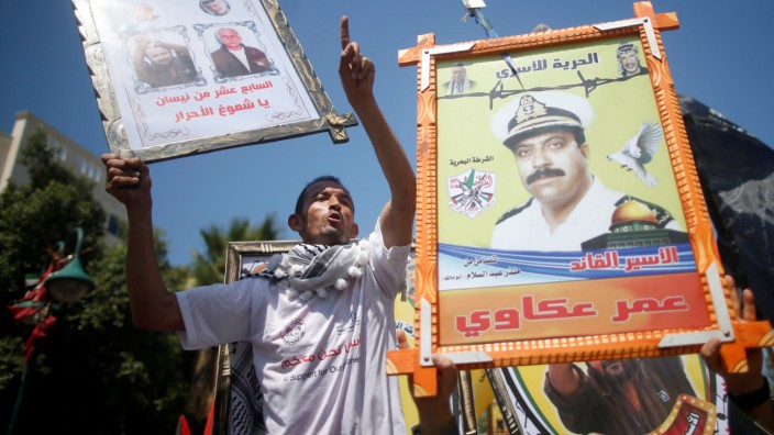 Demonstrators hold pictures of jailed Palestinians during a rally in support of Palestinian prisoners on hunger strike in Israeli jails, in Gaza City