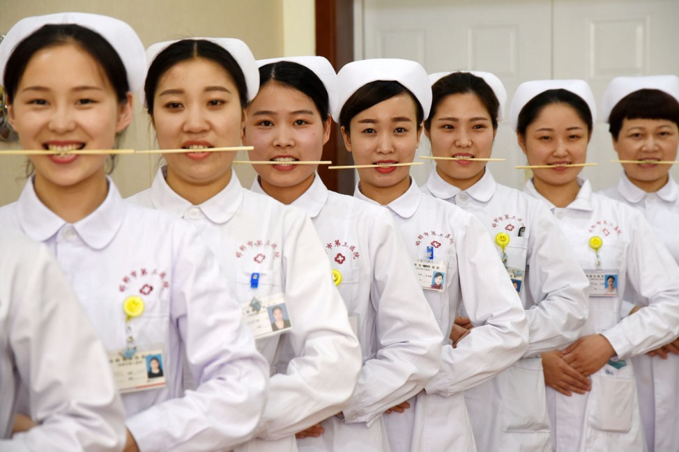 Nurses practice smiling with chopsticks in their mouths at a hospital in Handan