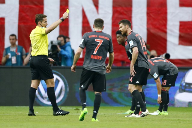 Bayern Munich's Xabi Alonso is shown a yellow card by the referee