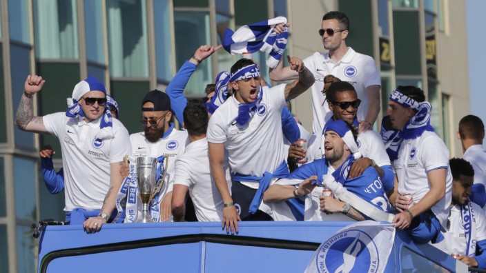 Brighton's Bruno celebrates with the trophy and team mates atop of the open top bus during the parade through Brighton