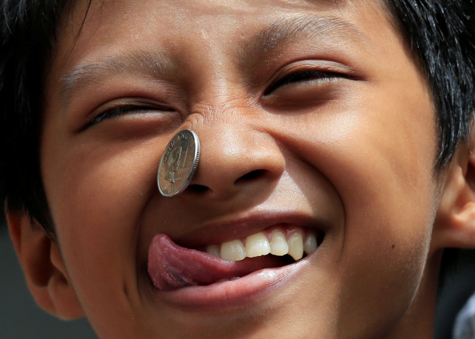 Boy use his face and tongue to move a coin from his forehead into his mouth, while participating in a parlour game, during a religious festival in Paranaque City