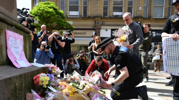 Anschlag in Manchester: "Schock der ganzen Nation": Ein Polizist ordnet Blumensträuße auf dem St. Ann's Square in der Innenstadt von Manchester, wo am Morgen nach dem Anschlag spontan eine Gedenkstätte für die Opfer des Selbstmordattentats entstanden war.