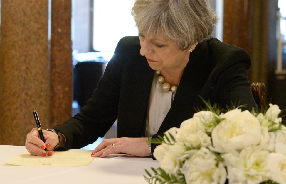 Britain's Prime Minister Theresa May writes a message for the book of condolences for the victims of the attack on Manchester Arena, at Manchester Town Hall in Manchester