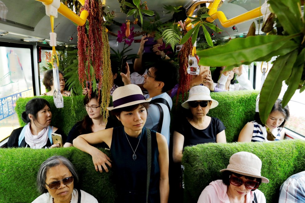 Passengers react inside a plant-filled bus, a special route that runs for 5 days, featuring the concept of integrating more green space into cities, in Taipei , Taiwan