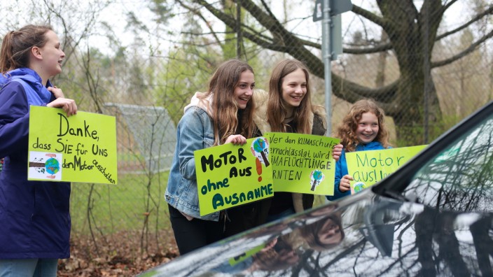 Umweltbildung an der Montessorischule Neubiberg: Schülerinnen der Emile Montessorischule weisen Autofahrer darauf hin, dass sie den Motor beim Warten an der Bahnschranke ausmachen sollen.