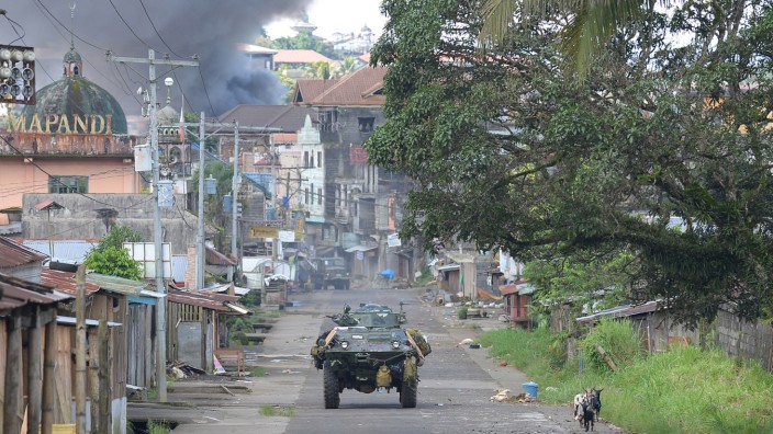 Philippinen: Einsatz in Marawi: Ein Panzer der philippinischen Armee fährt durch die umkämpfte Stadt. Im Hintergrund ist der Rauch sichtbar.